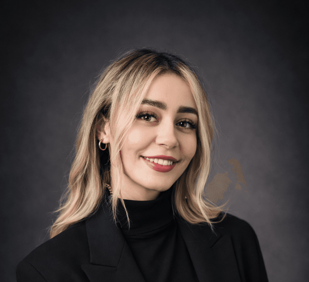 Professional corporate headshot of a smiling blonde woman in a black blazer.