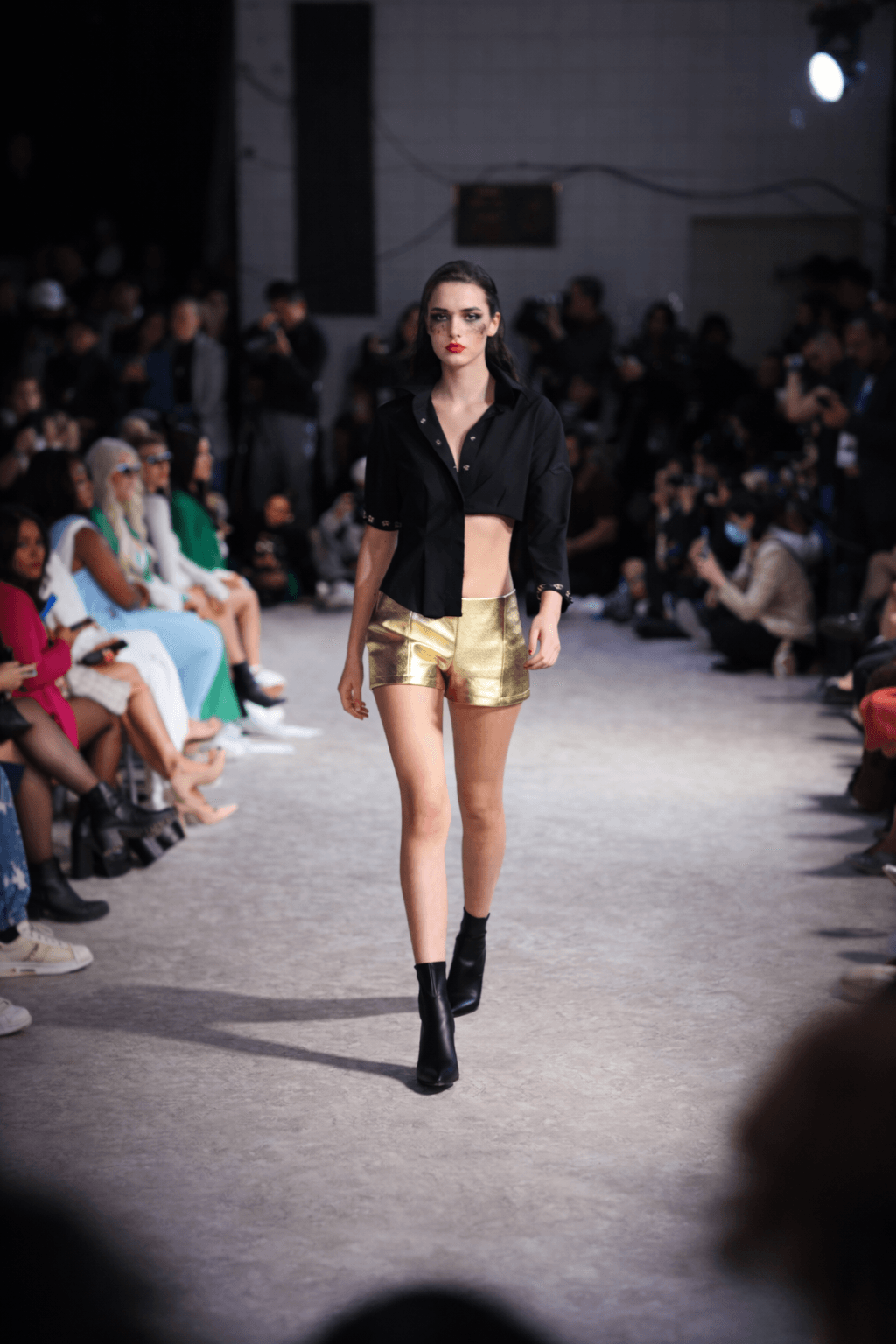 Black top and gold shorts in a spotlight