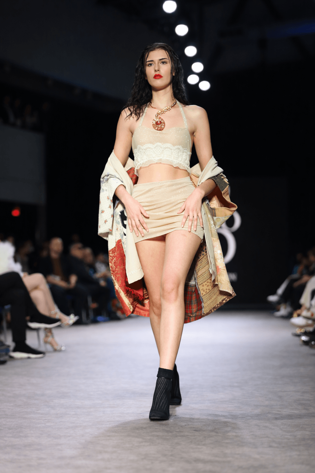 Model striding down the runway in a beige two-piece outfit