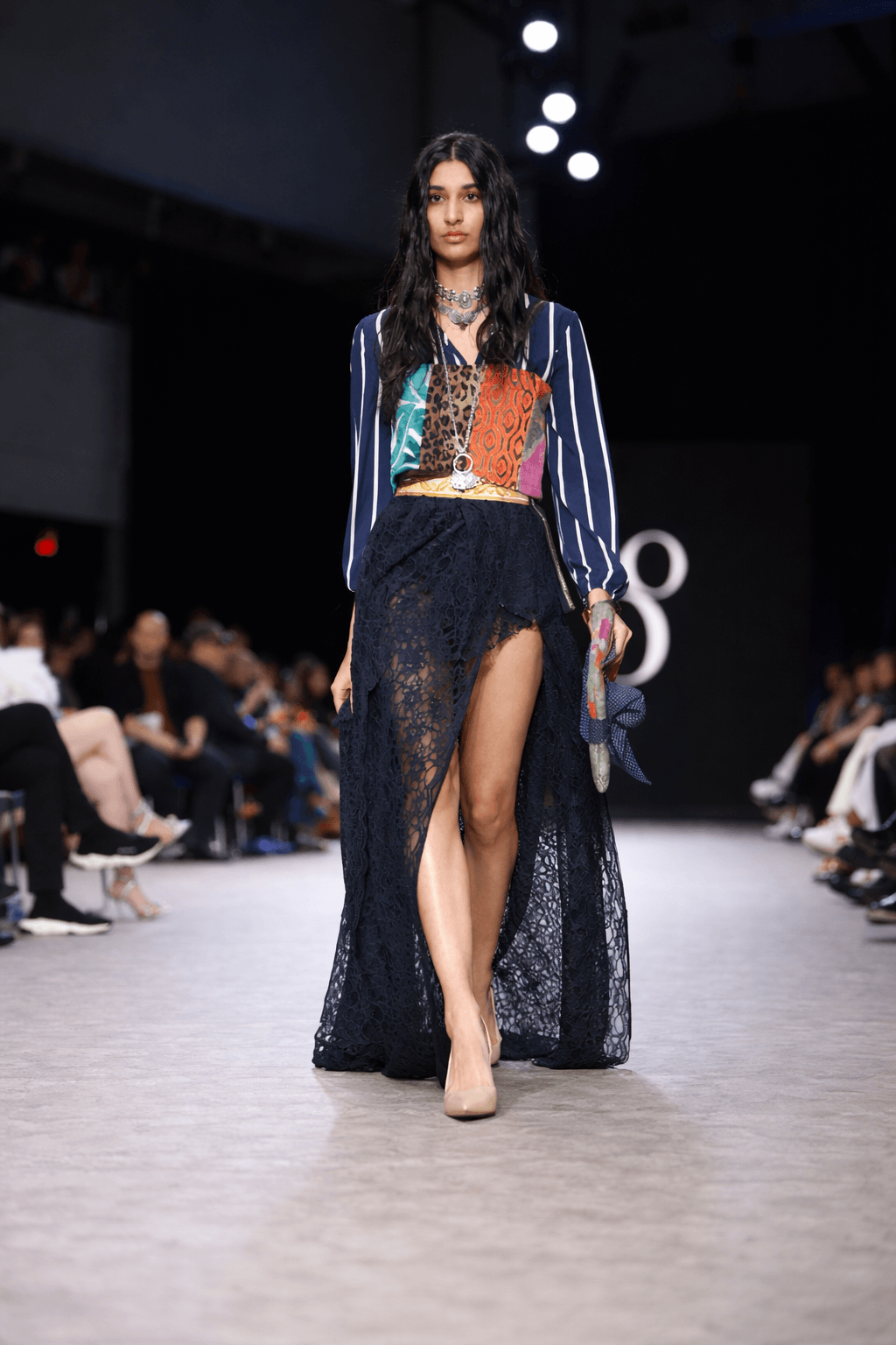 Model walking the VFW runway in a sheer black lace high-slit skirt