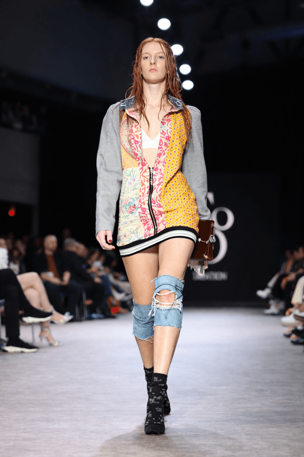 Model wearing a vibrant patchwork dress layered with a grey blazer