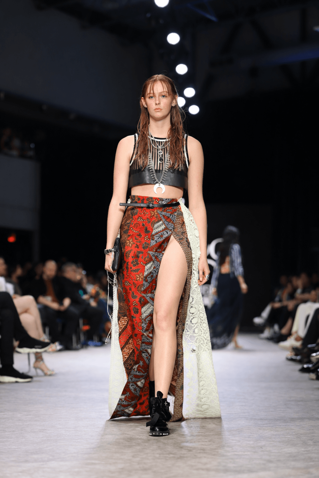 Runway model wearing a black crop top and a high-slit patterned wrap skirt